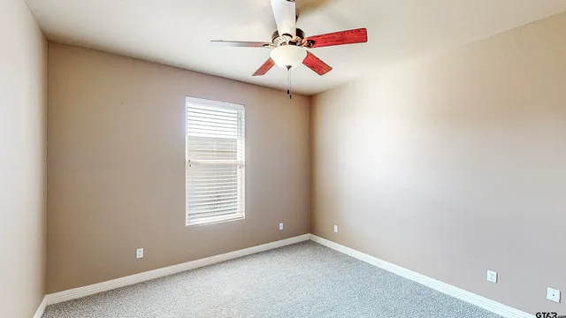 a view of an empty room with window and chandelier fan