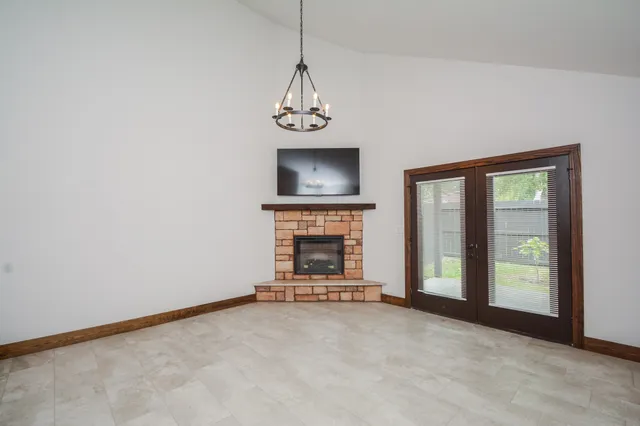 a view of an empty room with flat screen tv a fireplace and a window