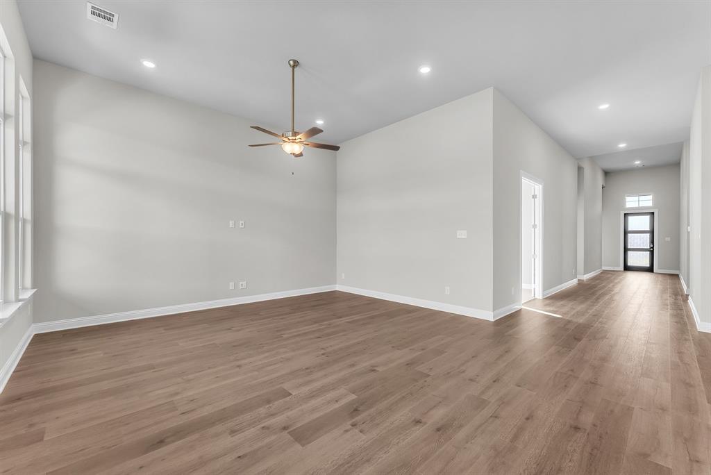 1215 Olive Drive Mansfield, TX 76063 - Photo 13 of 28 a view of an empty room with wooden floor and a ceiling fan