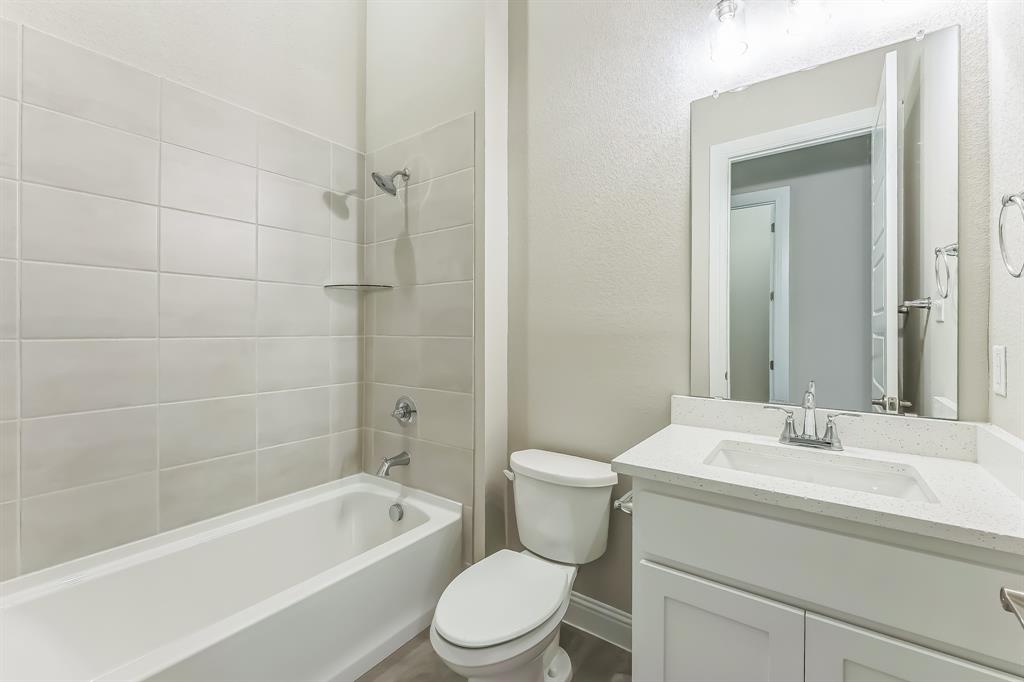 1215 Olive Drive Mansfield, TX 76063 - Photo 19 of 28 a bathroom with a bathtub shower sink mirror vanity and toilet