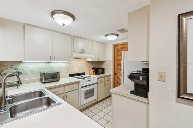 a kitchen with white cabinets and appliances