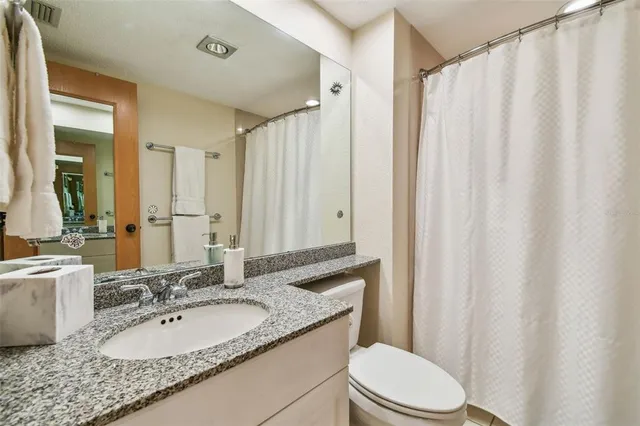 a bedroom with a bed and a lamp on dresser with a large window