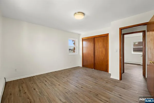 a view of an empty room with wooden floor and closet