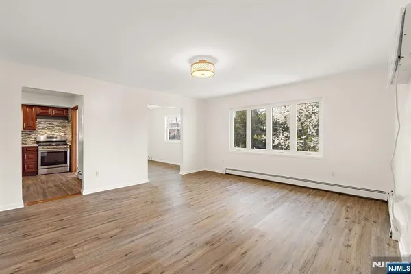 an empty room with wooden floor chandelier and windows