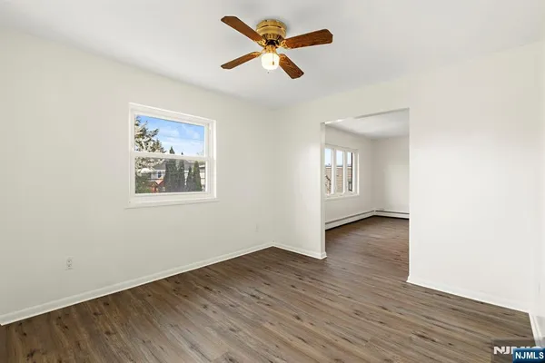 a view of an empty room with window and wooden floor