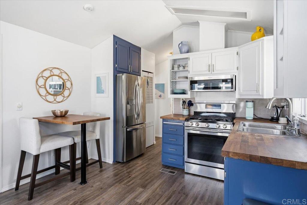 1624 North Coast Highway 101, Unit 6 Encinitas, CA 92024 - Photo 5 of 26 a kitchen with stainless steel appliances a stove a refrigerator a sink a stove and white cabinets with wooden floor