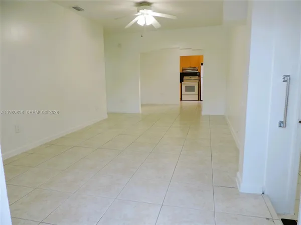 a view of an empty room with window and chandelier fan