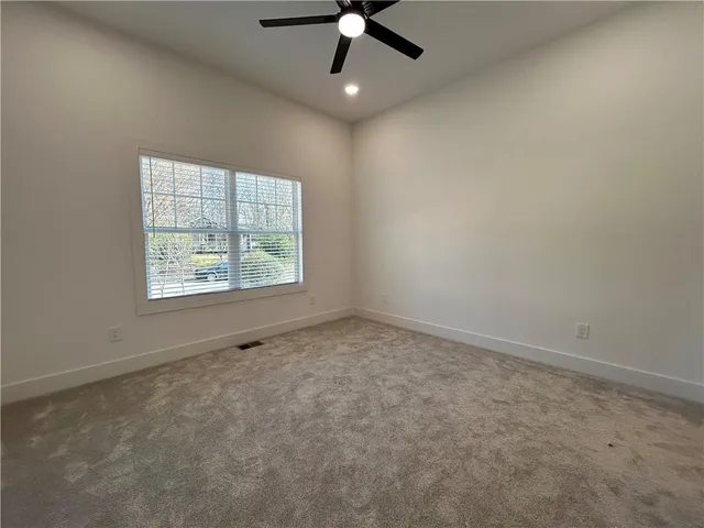 an empty room with a ceiling fan and carpet