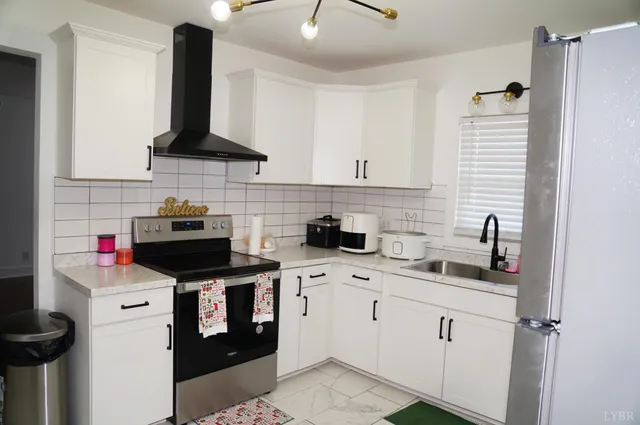 a kitchen with a sink dishwasher and white stove top oven with white cabinets