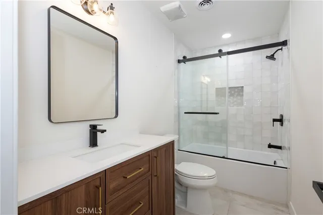 a bathroom with a shower sink vanity mirror and toilet