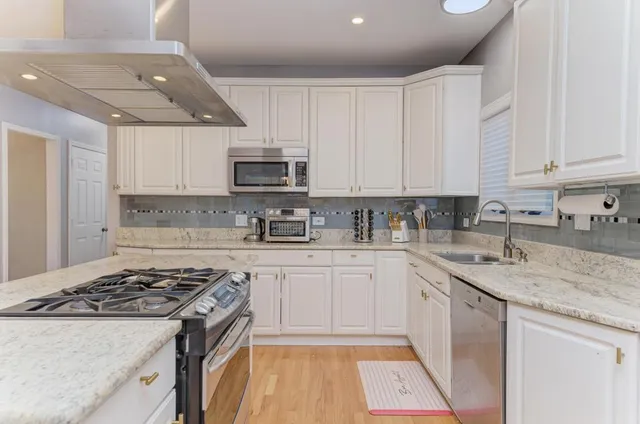 a kitchen with a sink appliances and wooden floor