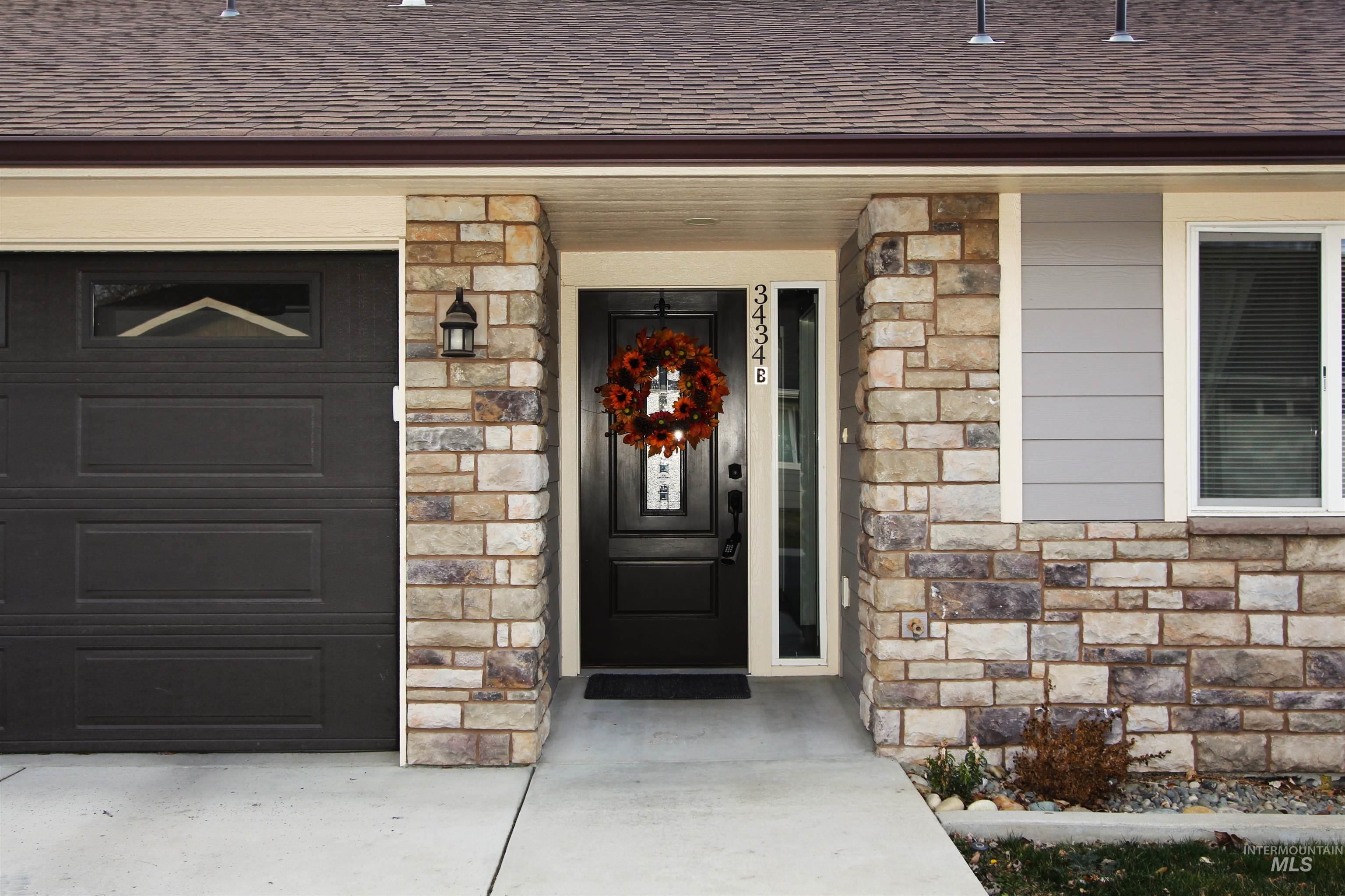 Doorway to property with stone siding and a shingled roof