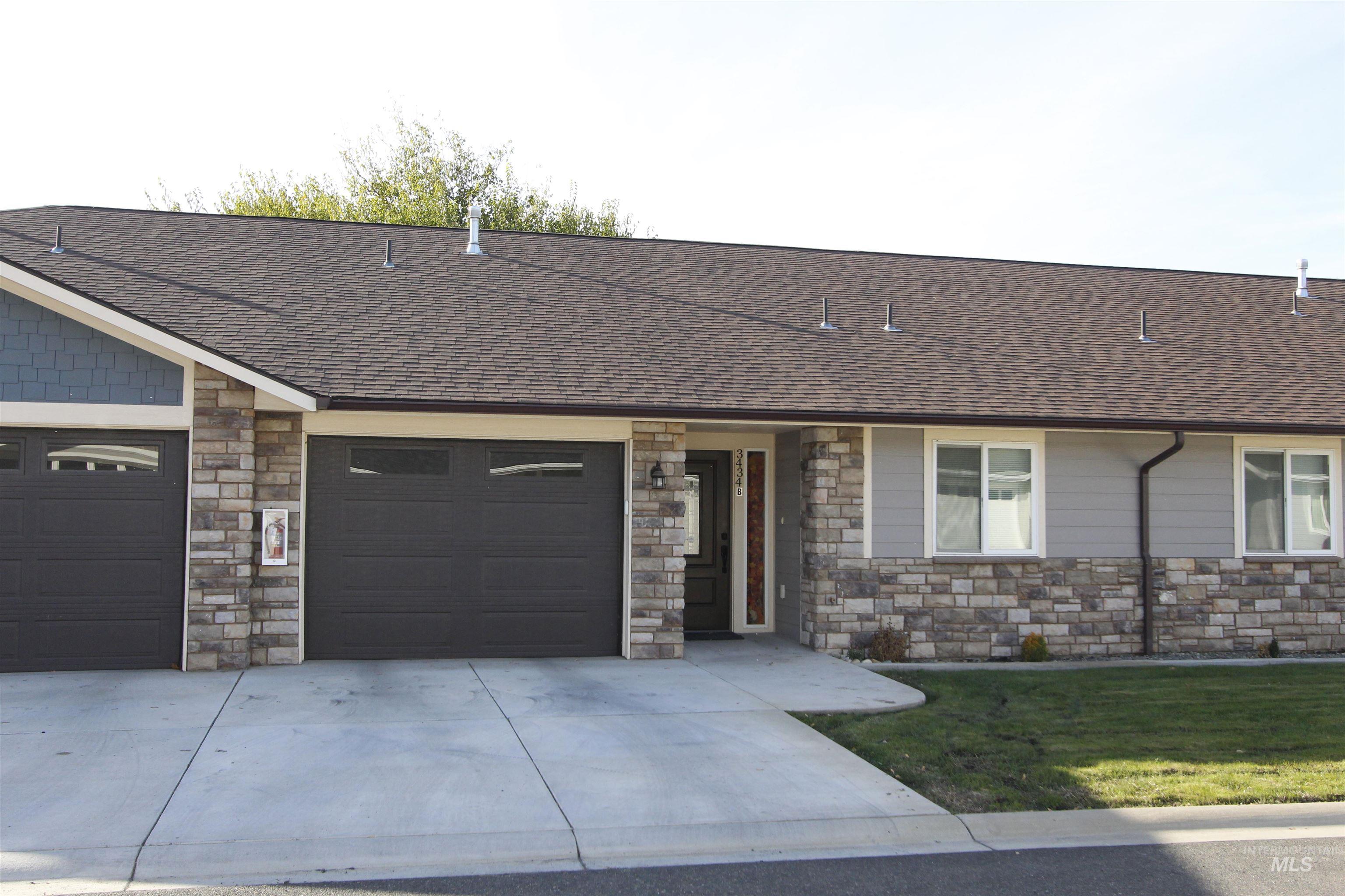 Ranch-style house featuring stone siding, driveway, a shingled roof, a front lawn, and a garage
