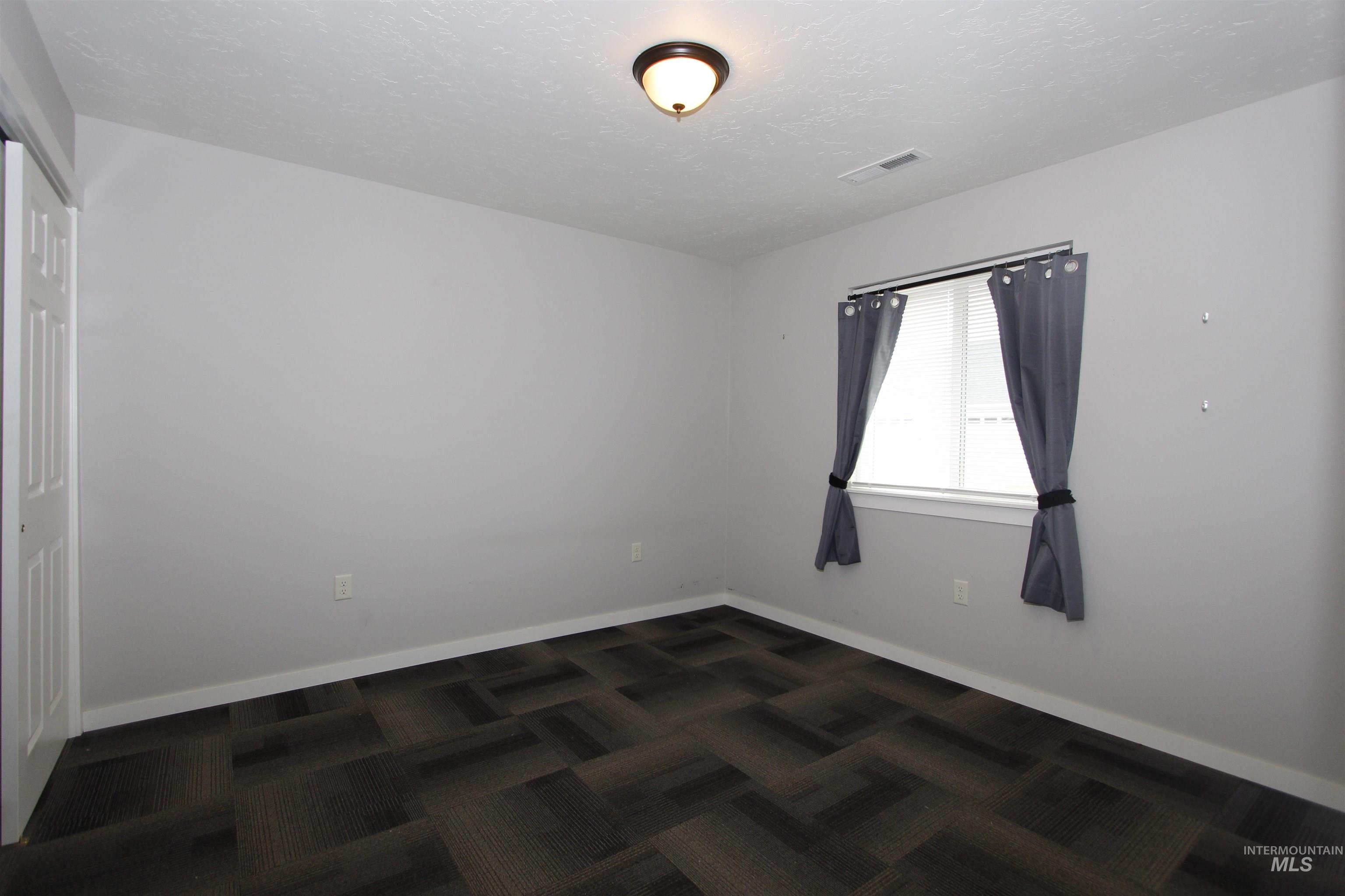3434 5th Street, Unit B Lewiston, ID 83501 - Photo 9 of 19 Spare room featuring dark colored carpet and a textured ceiling