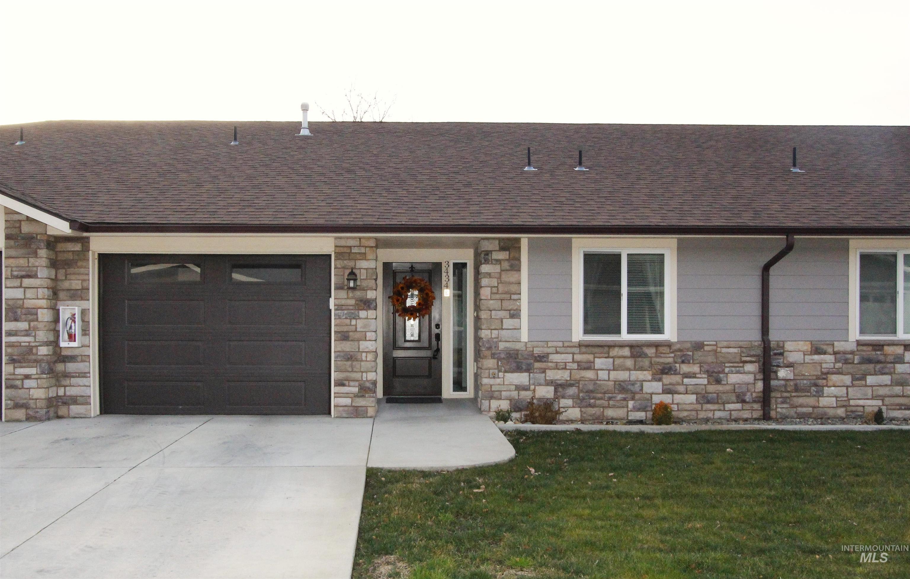 3434 5th Street, Unit B Lewiston, ID 83501 - Photo 2 of 19 View of front of property with an attached garage, stone siding, roof with shingles, driveway, and a front yard