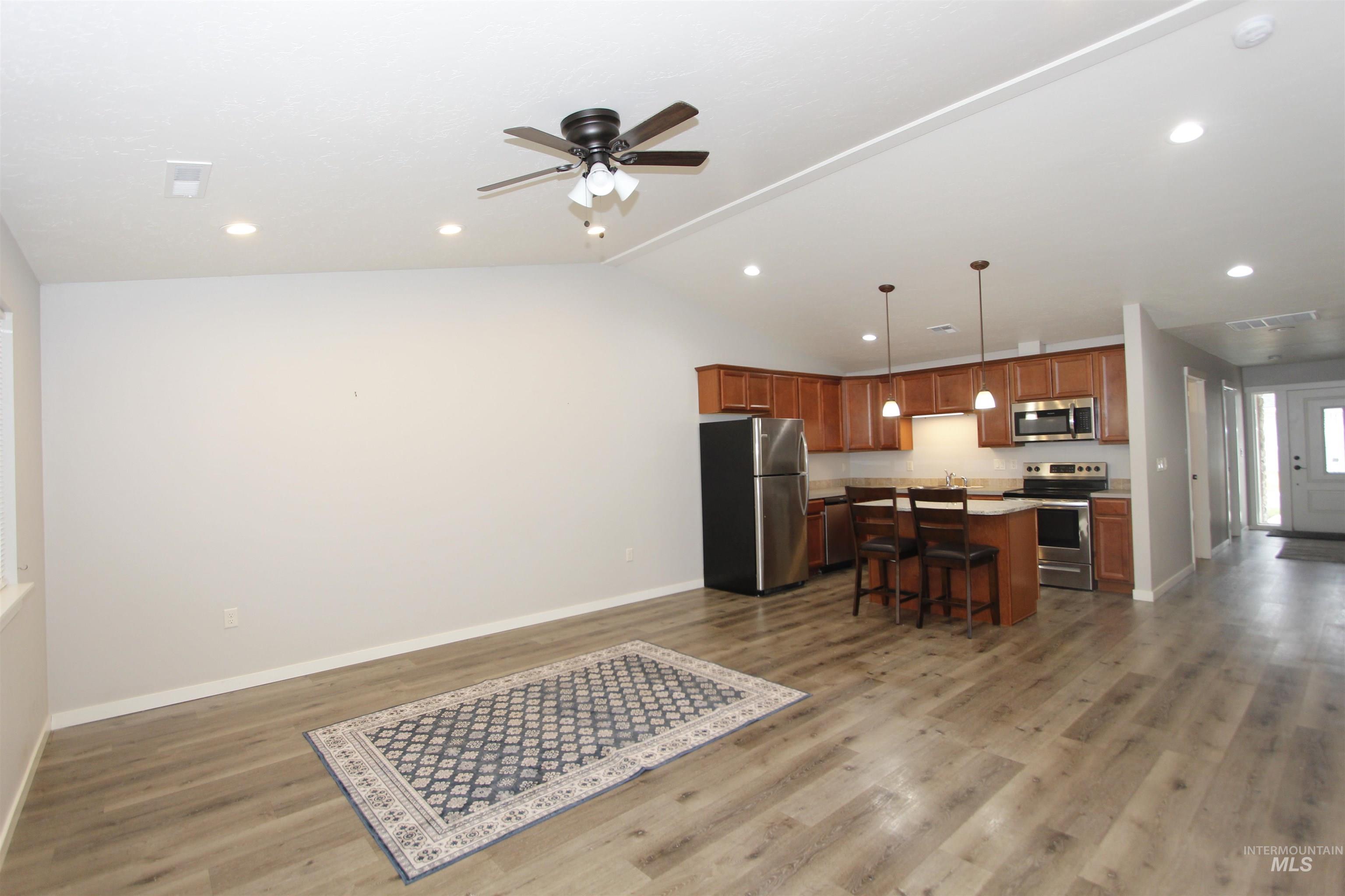3434 5th Street, Unit B Lewiston, ID 83501 - Photo 18 of 19 Kitchen with appliances with stainless steel finishes, brown cabinetry, vaulted ceiling, pendant lighting, and open floor plan