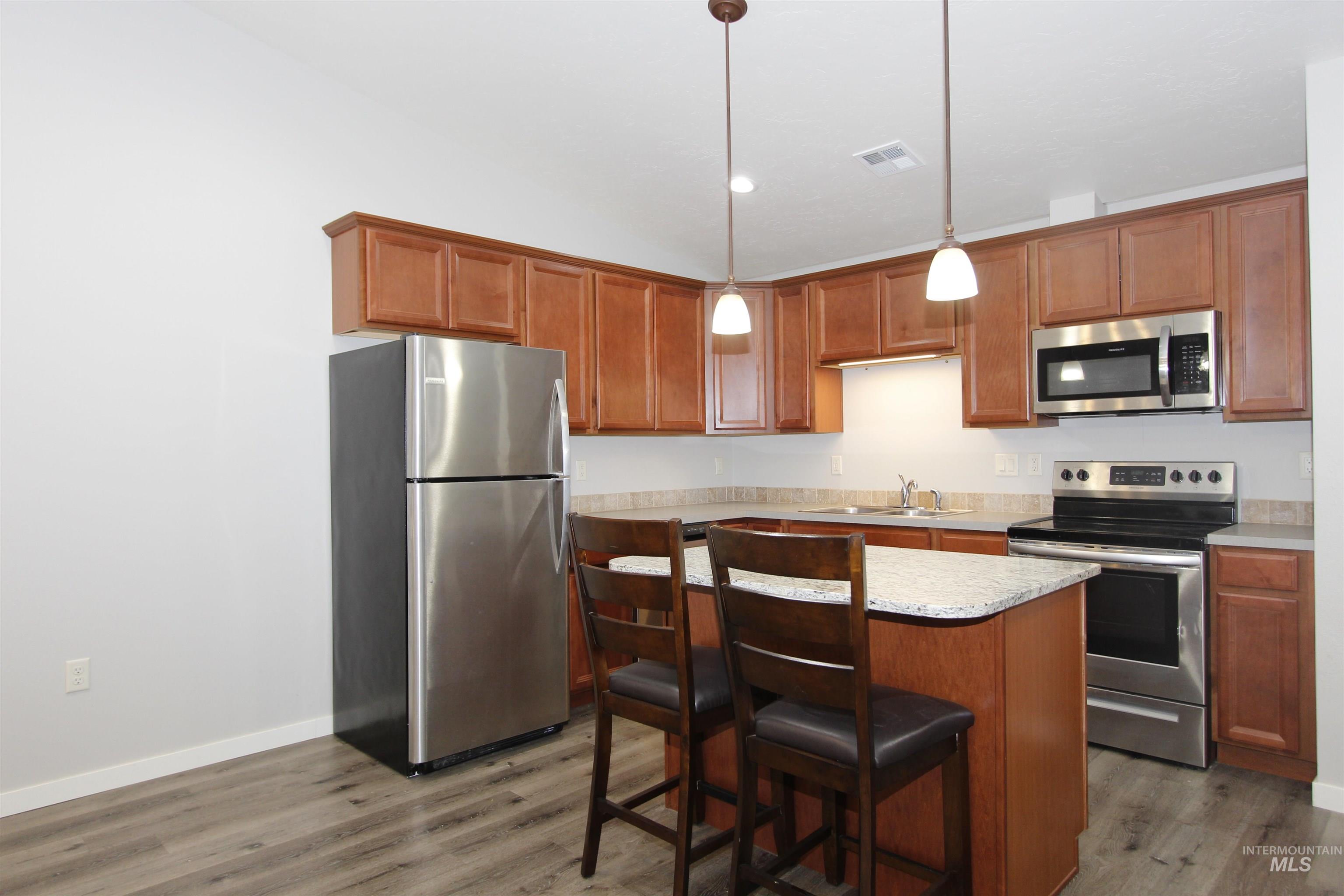 3434 5th Street, Unit B Lewiston, ID 83501 - Photo 3 of 19 Kitchen with appliances with stainless steel finishes, a kitchen island, hanging light fixtures, a breakfast bar, and light countertops