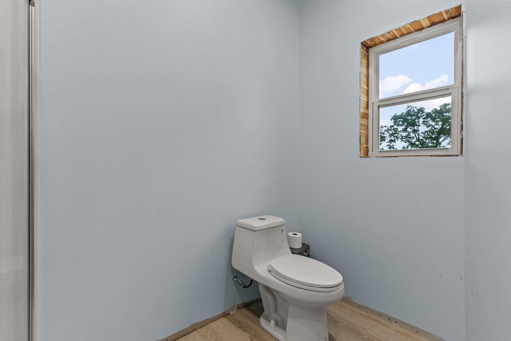 1129 Holly Road Gilmer, TX 75644 - Photo 20 of 31 Bathroom featuring a white toilet, light blue walls, and a window with a white frame