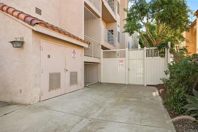 a view of a white house with a large tree and wooden fence
