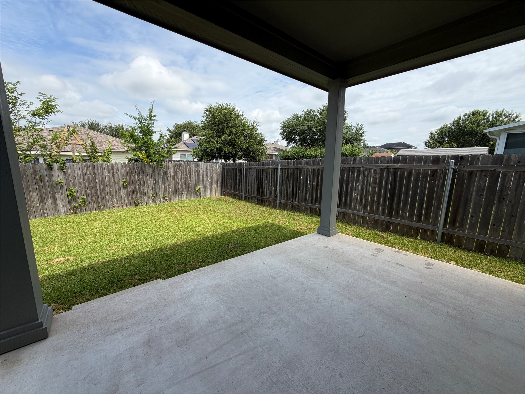419 Gettysburg Loop Elgin, TX 78621 - Photo 6 of 21 A well-maintained wooden fence encloses a lush, green yard with a spacious concrete patio.