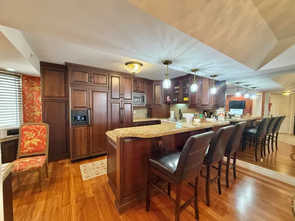 a dining room with stainless steel appliances granite countertop a table chairs and a refrigerator