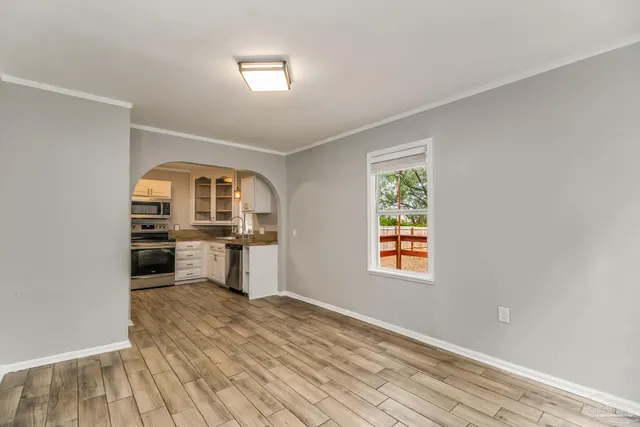a view of an empty room with a window and wooden floor