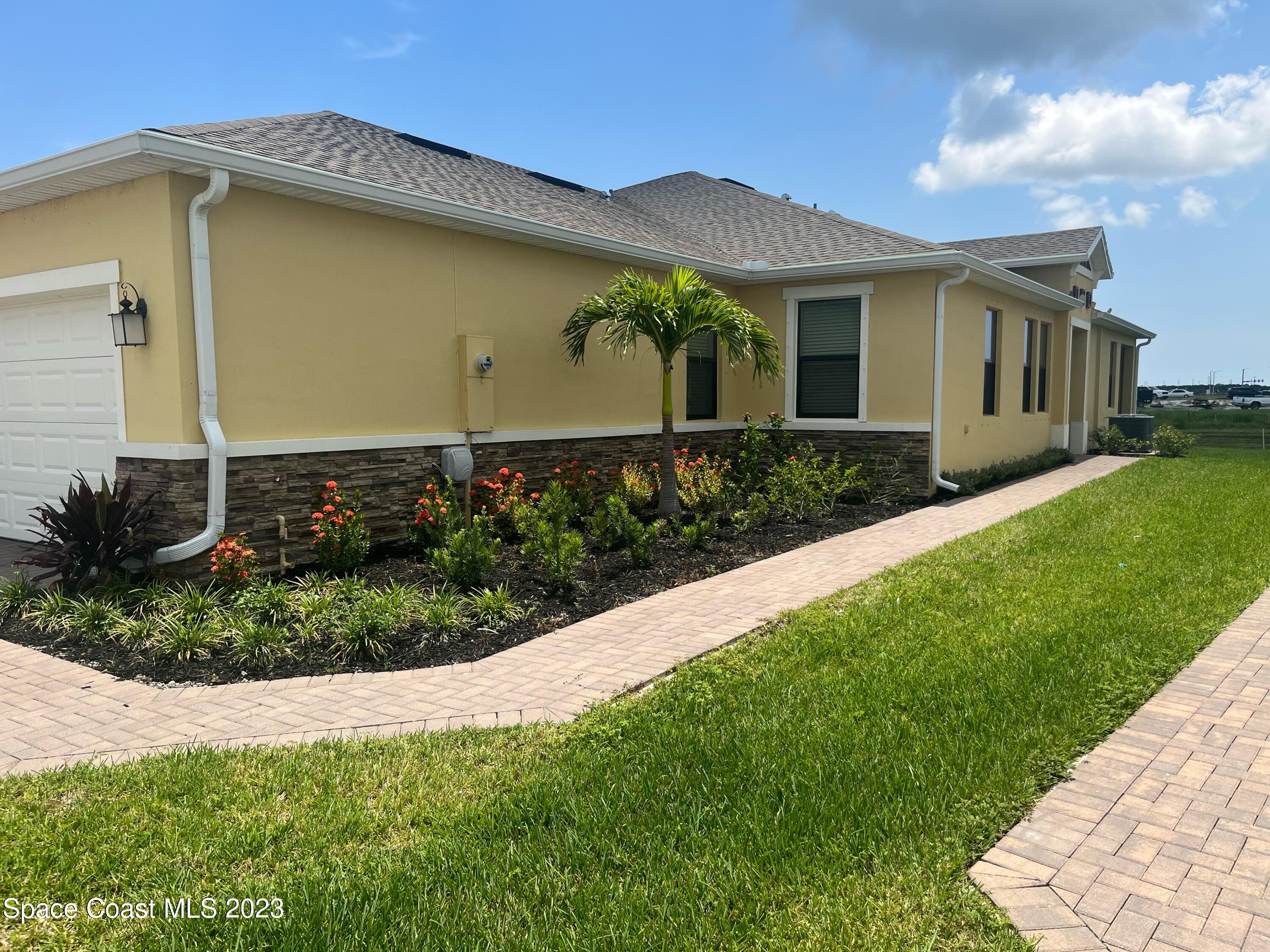 9753 Alister Drive Melbourne, FL 32940 - Photo 3 of 42 a front view of a house with a garden
