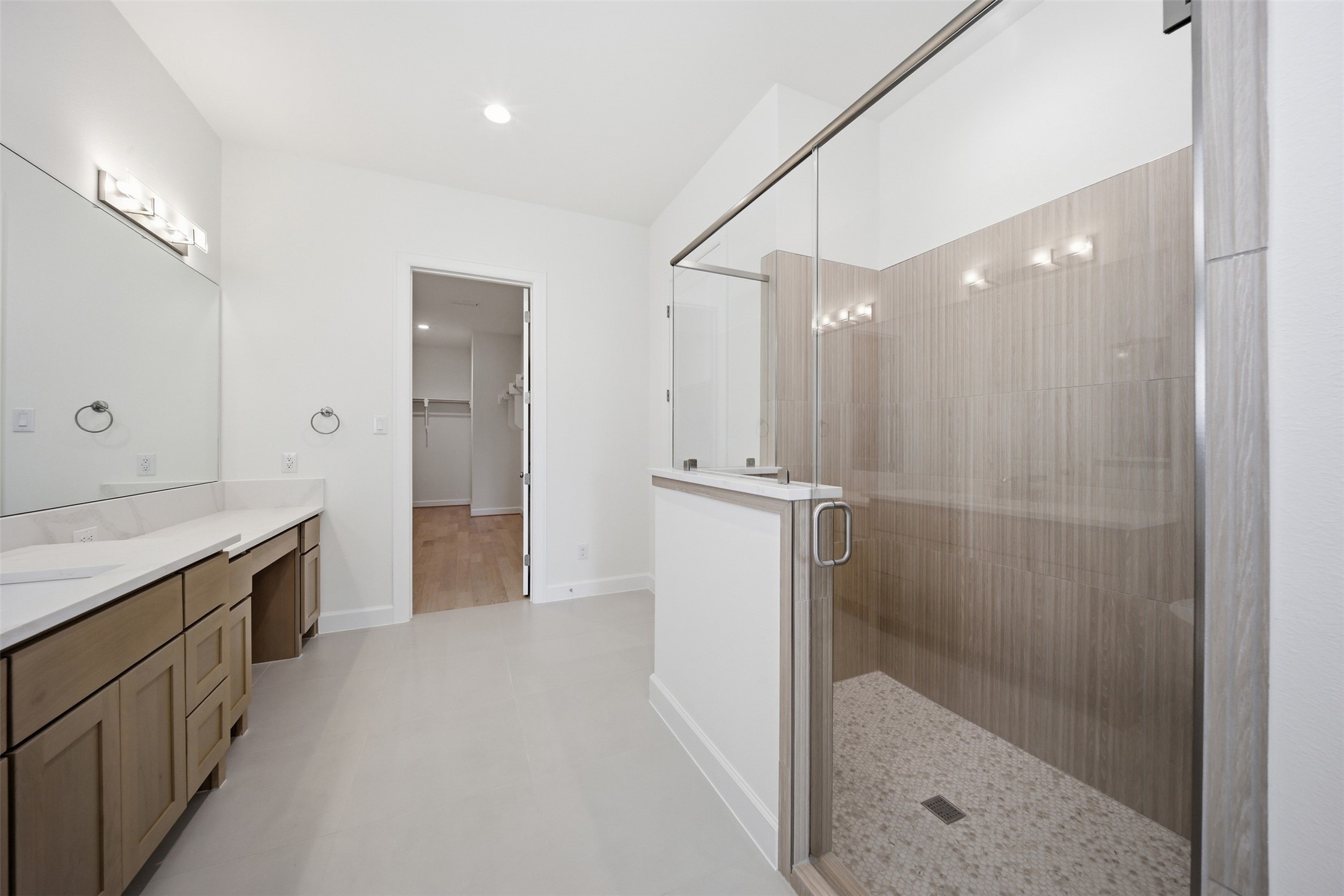 416 Venado View Court Conroe, TX 77304 - Photo 18 of 34 Elegant primary bath showcasing dual vanities, designer finishes, oversized walk-in shower with floor-to-ceiling tile, and seamless access to the expansive walk-in closet for elevated everyday living.