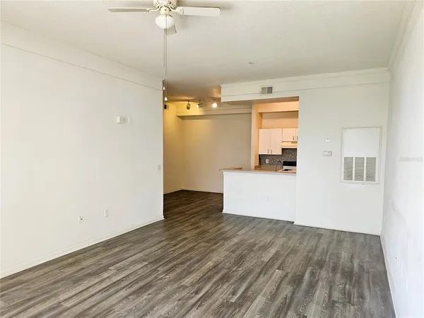 an empty room with wooden floor and fan