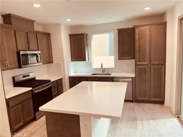 a kitchen with kitchen island granite countertop stainless steel appliances a refrigerator stove top oven and sink