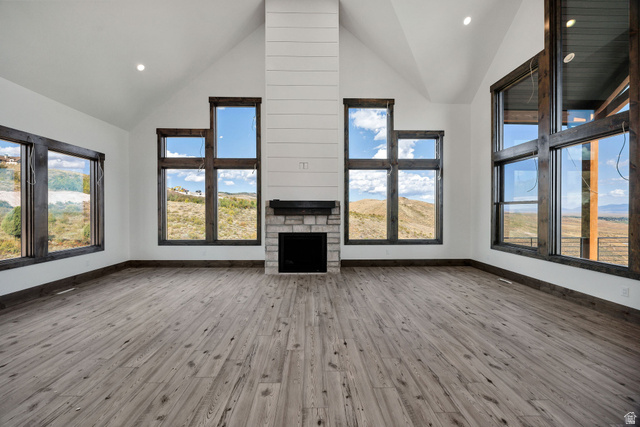 300 Knoll Loop, Unit 227 Fish Haven, ID 83287 - Photo 7 of 56 Unfurnished living room with a high ceiling, a stone fireplace, light wood-type flooring, and recessed lighting