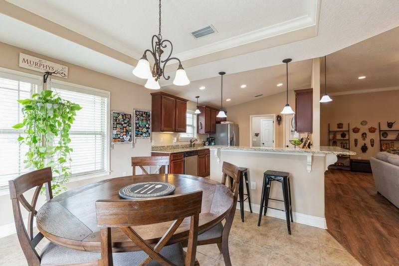 2693 Hartman Court Navarre, FL 32566 - Photo 14 of 34 a dining room with kitchen island a dining table wooden floor stainless steel appliances and a chandelier
