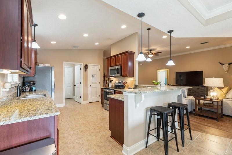 2693 Hartman Court Navarre, FL 32566 - Photo 8 of 34 a kitchen with stainless steel appliances kitchen island granite countertop a stove top oven a sink a dining table and chairs with wooden floor