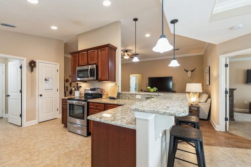 2693 Hartman Court Navarre, FL 32566 - Photo 9 of 34 a kitchen with stainless steel appliances kitchen island granite countertop a stove refrigerator and cabinets