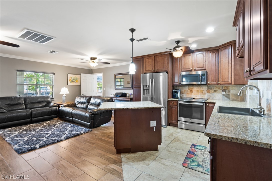 1447 Collins Road Fort Myers, FL 33919 - Photo 12 of 34 a kitchen with kitchen island granite countertop a refrigerator a stove top oven a sink dishwasher and wooden cabinets