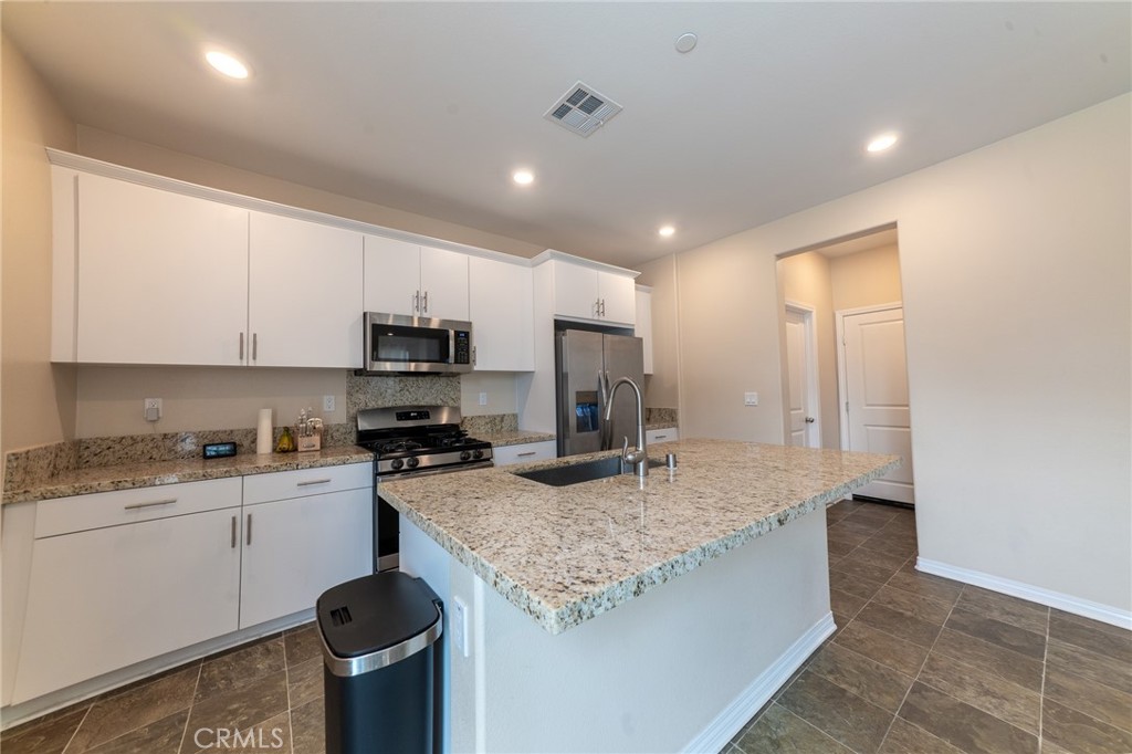 2464 Gunner Ridge Way Rialto, CA 92377 - Photo 8 of 42 a kitchen with stainless steel appliances granite countertop a sink stove and refrigerator