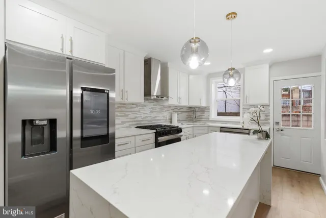 a kitchen with granite countertop a refrigerator a sink a stove and cabinets