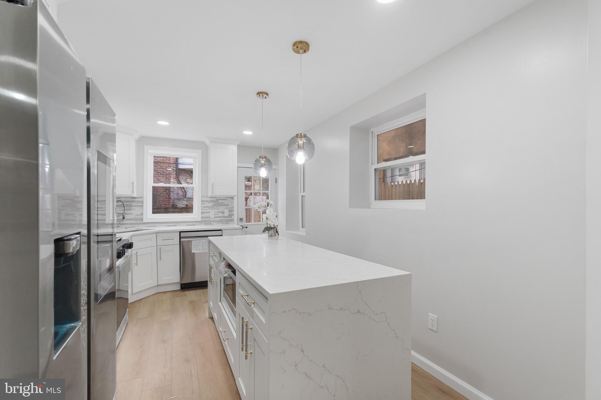 1203 Moore Street Philadelphia, PA 19148 - Photo 9 of 41 a large kitchen with a refrigerator a sink dishwasher a stove and white cabinets with wooden floor