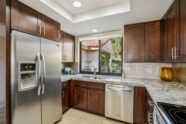 a kitchen with stainless steel appliances granite countertop a refrigerator a sink a stove and washer