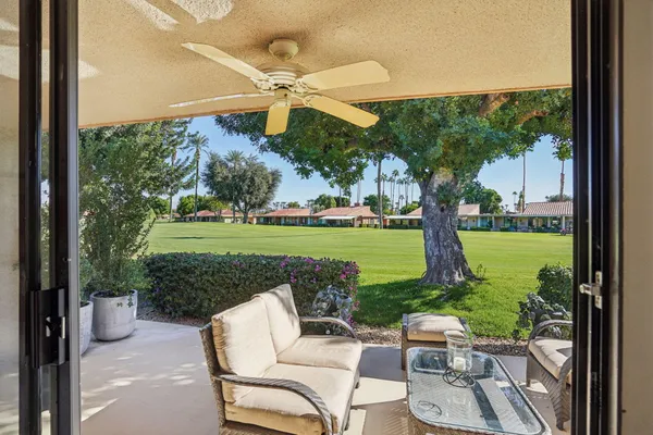 a view of a patio with a table chairs fire pit and a yard