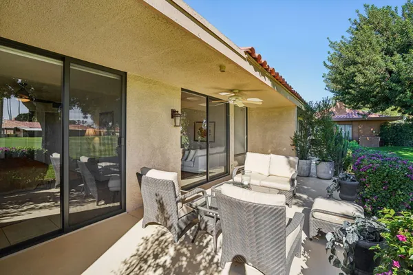 a patio with table and chairs and potted plants