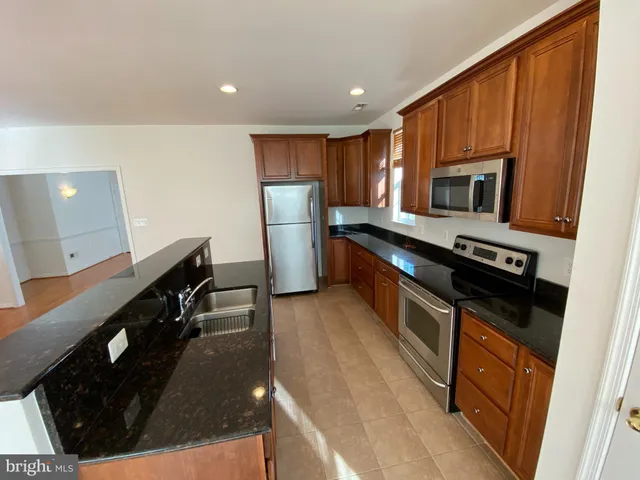 a kitchen with stainless steel appliances a stove a sink a refrigerator and a microwave