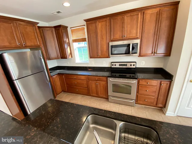a kitchen with granite countertop a refrigerator stove and microwave