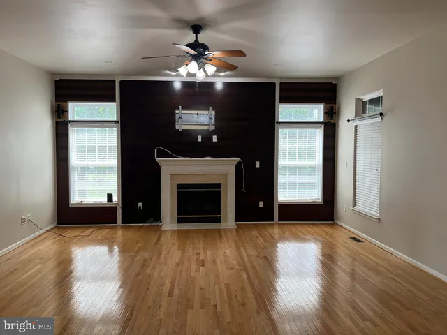 an empty room with windows chandelier and fireplace