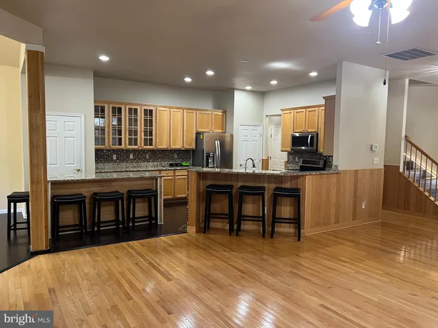 a kitchen with stainless steel appliances granite countertop a stove top oven a sink dishwasher a dining table and chairs with wooden floor