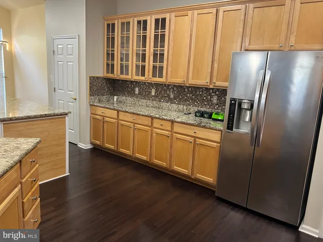 a kitchen with stainless steel appliances granite countertop a refrigerator a stove and a sink with wooden floor