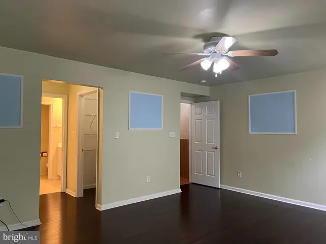 a view of a livingroom with a large window a ceiling fan and wooden floor