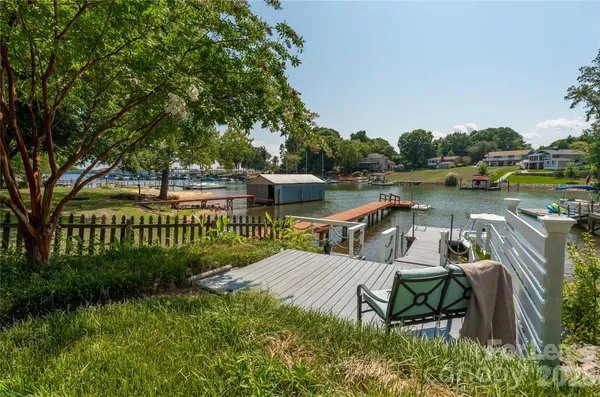 a view of a lake with a table and chairs next to a yard