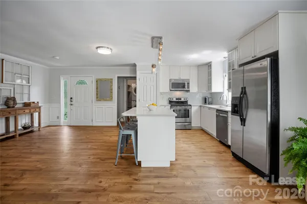 a kitchen with stainless steel appliances granite countertop a refrigerator a stove top oven a sink dishwasher and white cabinets with wooden floor