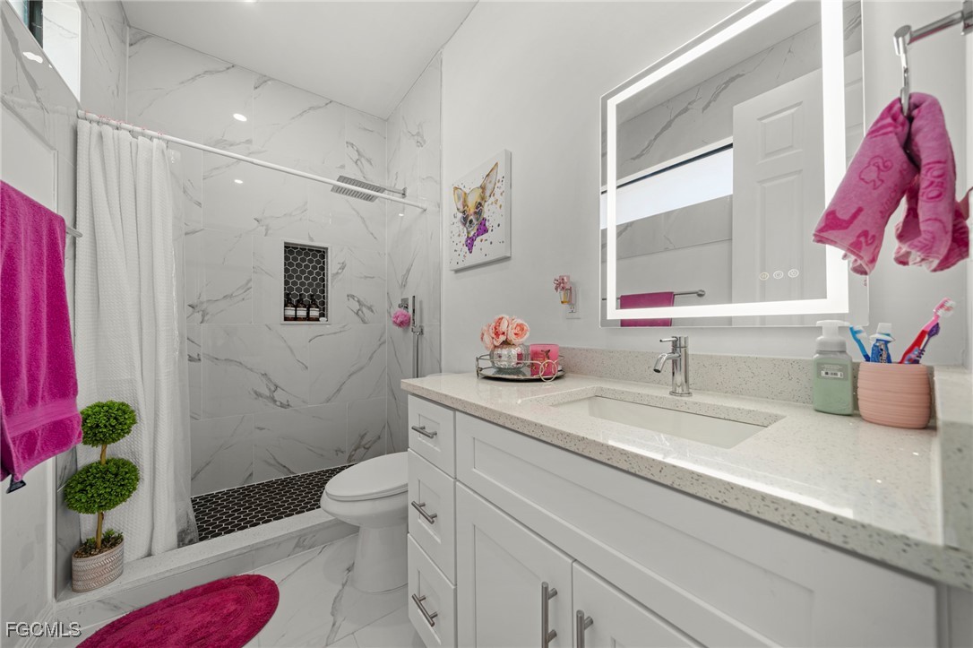 3713 25th Street Southwest Lehigh Acres, FL 33976 - Photo 18 of 31 a bathroom with a sink a toilet and a shower